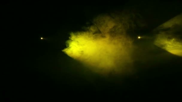 Gele lichtstralen van profielspots in het donker in een rook deken — Stockvideo