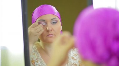 Evli bir Jewess aynaya yansıyan göz farı ile makyaj yapar