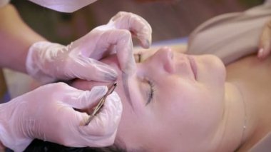 Beautician cımbız ile müşterilerin kaşları düzeltir.