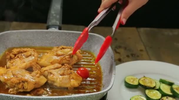 Женская рука кладет ломтики овощей с щипцами курица на гриль сковороду и наливает соус . — стоковое видео