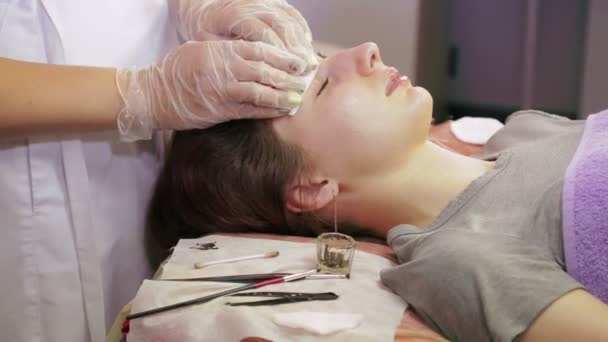 Die Kosmetikerin wäscht die überschüssige Henna von den Augenbrauen der Kundin — Stockvideo