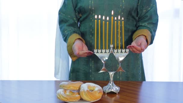 Еврейка зажигает свечи на Хануке в красивом подсвечнике . — стоковое видео