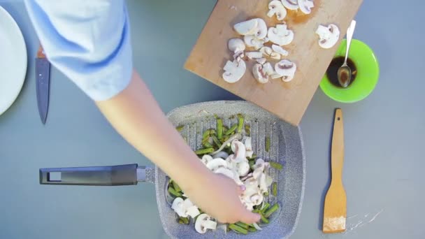 К фольге и луку женщина добавляет нарезанные шампиньоны на сковороде . — стоковое видео