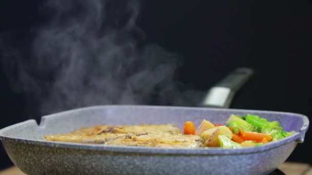 鍋で魚や野菜をかき混ぜるためのトングを持つ女性の手. — ストック動画