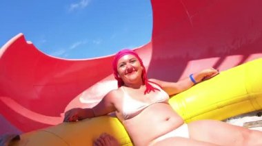 Yüzme çemberinde genç bir kadın su kaydırağı iner ve ekstrem sporlardan çığlıklar atar..