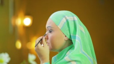 Ayna önünde Müslüman kadın parlak gölgeler de göz makyajı yapar