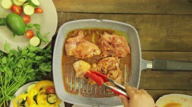 WOMANS el maşa ile bir ızgara Pan tavuk parçaları döner.