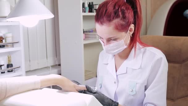 Mulher manicure com luvas em um salão de beleza prega um cliente com um arquivo de unhas antes de aplicar revestimento em gel — Vídeo de Stock