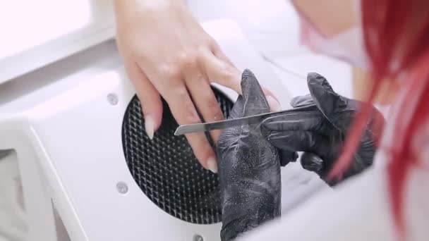 Женщина в перчатке маникюрша в салоне красоты ногтей клиента с пилкой для ногтей перед нанесением гелевого покрытия . — стоковое видео
