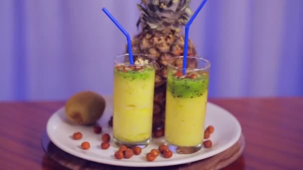 Стакан с фруктовым коктейлем на белой тарелке с фруктами и орехами и классом жестов — стоковое видео