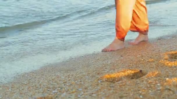 Γυναικεία πόδια με πλατύ παντελόνι ξυπόλητη πάνε κατά μήκος της άκρης του θαλάσσιου νερού — Αρχείο Βίντεο