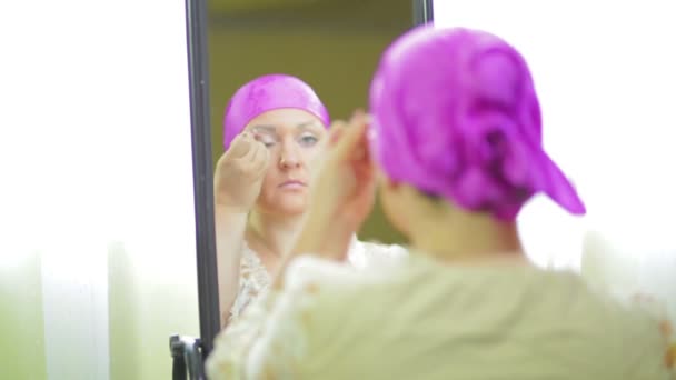 Een getrouwde Jewess voor de spiegel doet Oogmake-up met lichte schaduwen met een borstel — Stockvideo