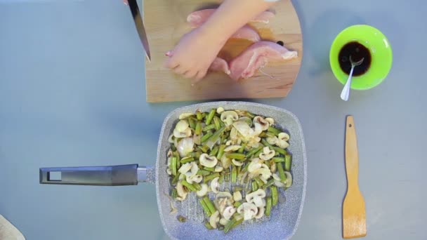 Frauenhand schneidet Hühnerbrust auf Teller auf Holzbrett. — Stockvideo