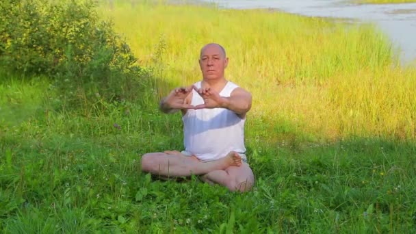 Ένας μεσήλικα άνθρωπος αναπνέει γιόγκα και διαλογίζεται στη λίμνη το πρωί. — Αρχείο Βίντεο