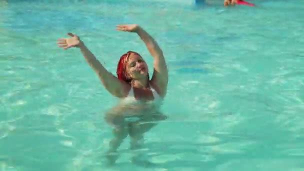Mujer bronceada con coletas bailando en la piscina con las manos levantadas — Vídeo de stock