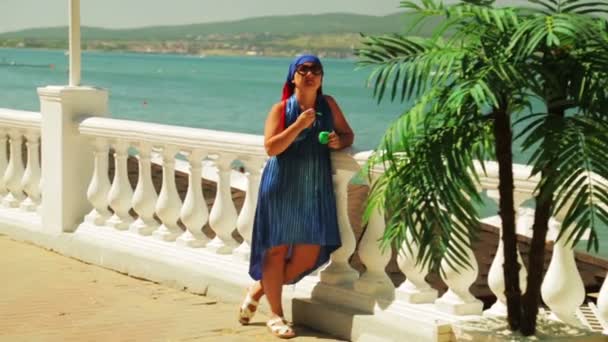 Une jeune femme sur la promenade au bord de la mer mange de la glace — Video