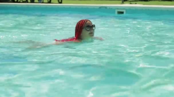 Židovka ve slunečních brýlích plave v bazénu — Stock video