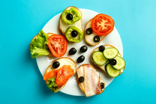 Tabaktaki mavi arka planda çeşitli sandviçler..