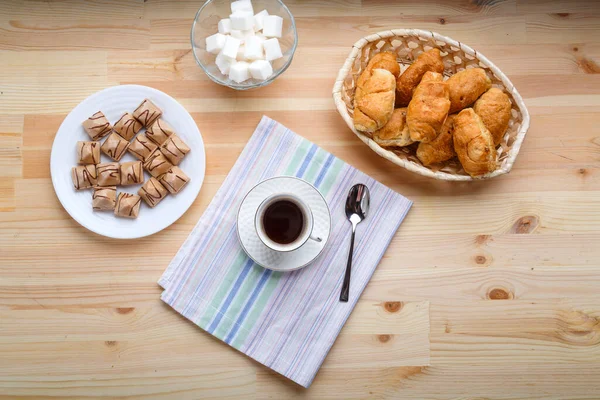 Kopje koffie op servetten op een houten tafel met croissants en wafels. — Stockfoto