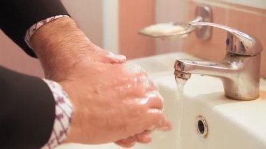 Halka açık bir yerde ellerini sabunla yıkayan bir adam.