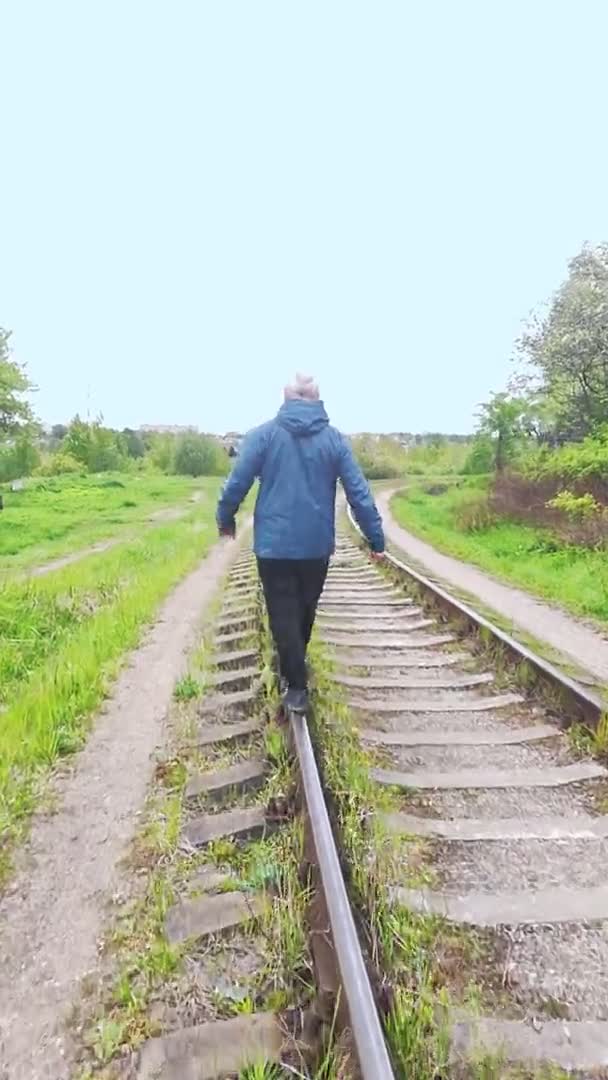 一个人沿着铁路的铁轨走着，穿过铁路的每一条铁路. — 图库视频影像