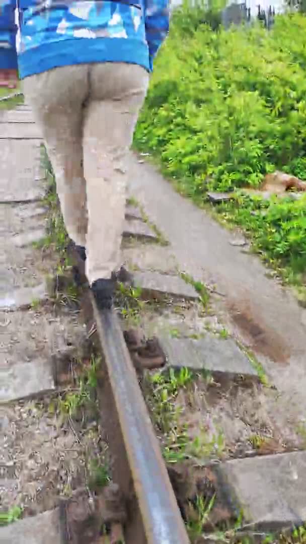 Θηλυκά πόδια που περπατούν στις ράγες του σιδηροδρόμου. Κάθετη — Αρχείο Βίντεο