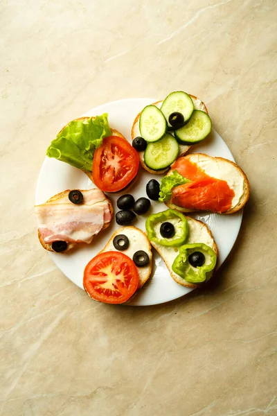 Verschiedene Sandwiches mit Fischspeck und Gemüse auf einem hellen Tisch. — Stockfoto