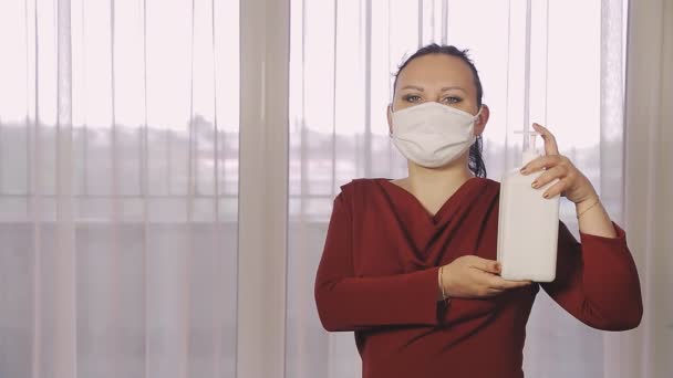 Een vrouw op een openbare plaats met een beschermend masker desinfecteert haar handen met een professioneel ontsmettingsmiddel — Stockvideo