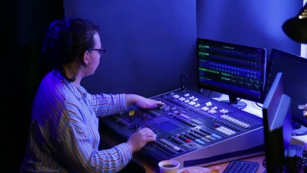 Jeune femme avec des lunettes ingénieur illuminateur programmes la lumière pour le spectacle et boit du café . — Video