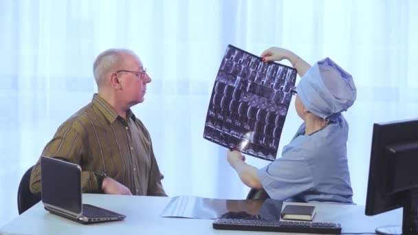 Uma médica aconselha um paciente do sexo masculino sobre os resultados da ressonância magnética da coluna vertebral — Vídeo de Stock