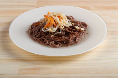 Yukardan gelen soba karabuğdaylı erişte ve sebzeli beyaz tabak..