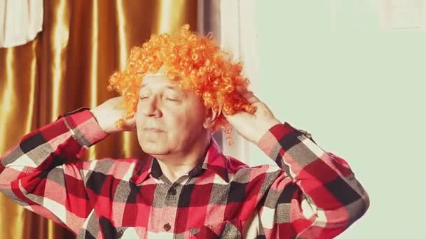 Ένας άντρας χορεύει με περούκα καρναβαλιού με κόκκινες μπούκλες. — Αρχείο Βίντεο