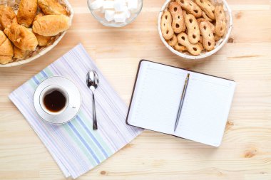 Bir fincan kahve peçetenin üzerinde Tahta bir masa üzerinde Şekerler ve not defteriyle.