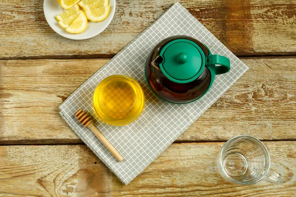 Wasserkocher mit Tee und Honig mit Zitrone auf dem Tisch. — Stockfoto