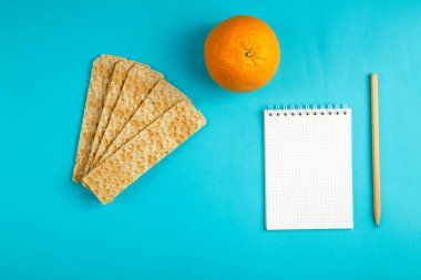 diyet ekmeği, portakal ve mavi arka plana kalori yazmak için bir defter..