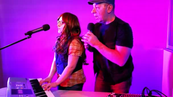 Un hombre y una mujer en un estudio de grabación cantan en un micrófono. Toca el sintetizador. . — Vídeos de Stock