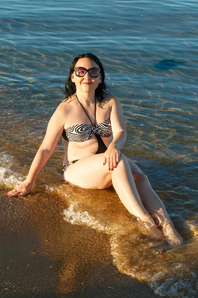 Una donna in costume da bagno prende il sole sulla spiaggia al mattino . — Foto Stock