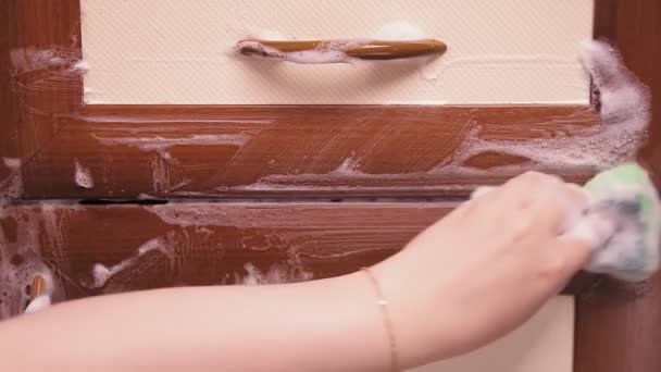 Samice ruční houba s pracím práškem myje kuchyňský nábytek