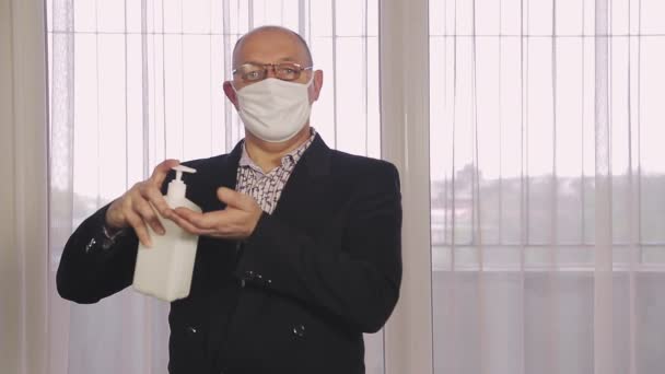 Een man op een openbare plaats met een beschermend masker desinfecteert zijn handen met een professioneel antisepticum — Stockvideo