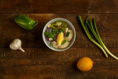 Hafif bir tabak Vietnam Pho çorbası ve ahşap bir masada tavuk..