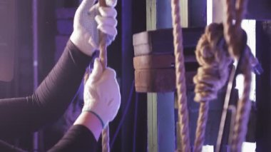 Kadın bir mühendisin elleri yükü kabloyla kaldırıyor..