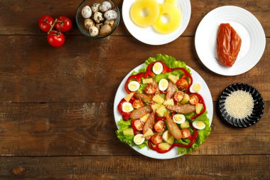 Çeri domatesli Pan-Asya salatası, tütsülenmiş tavuk, ananas ve susam tohumları ve ahşap bir masa üzerinde çeşitli malzemeler..