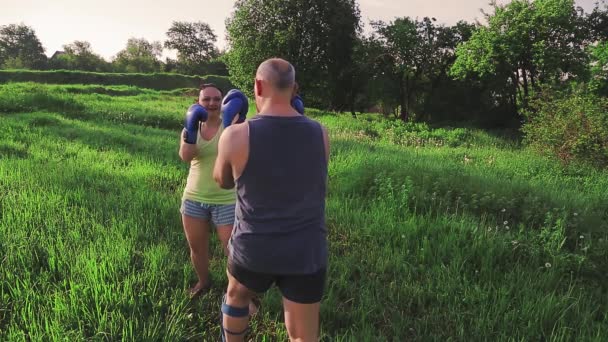 Homem e mulher no verão no parque estão envolvidos em boxe tailandês com luvas — Vídeo de Stock