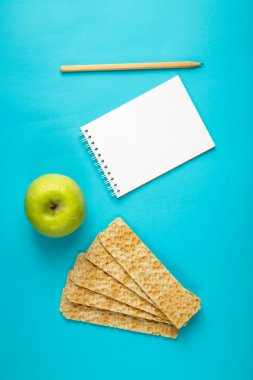 diyet ekmeği, yeşil elma ve mavi arka plana kalori yazmak için bir kalemle birlikte not defteri..