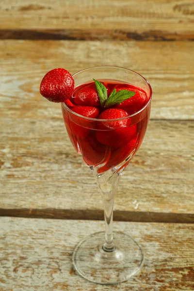 Kristallglas mit Erdbeersaft und frischen Beeren und Minze drinnen auf einem Holztisch. — Stockfoto