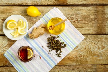 Bir fincan limonlu bal zencefilli çay ve masaya serpiştirilmiş çay..