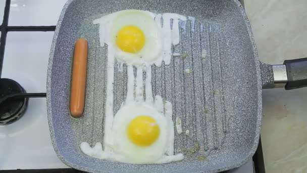 一只手把香肠放在一个煎锅里，上面放着煎蛋 — 图库视频影像