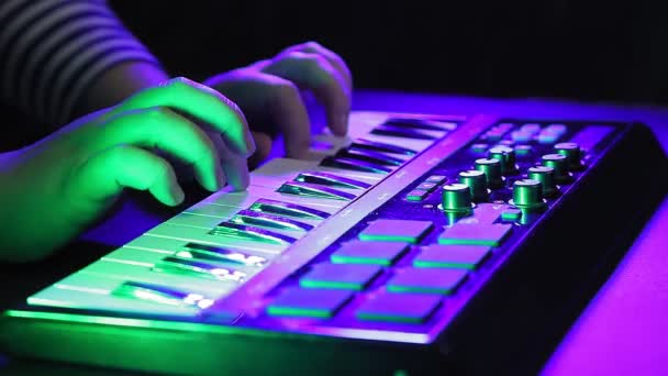 Γυναικεία χέρια παίζουν σε ένα πληκτρολόγιο MIDI, ηχογράφηση μουσικής, ενώ βλέποντας ένα φορητό υπολογιστή — Αρχείο Βίντεο
