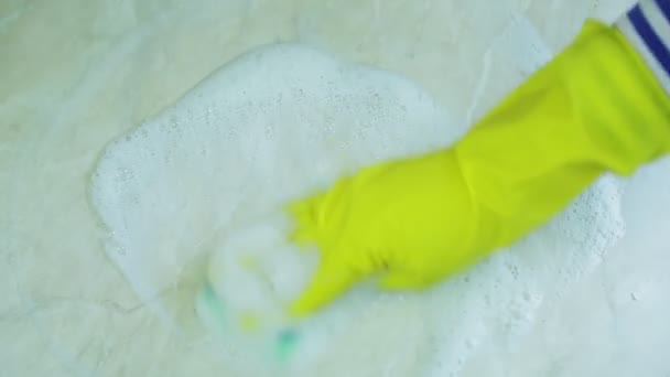 Uma mão em uma luva de borracha lava a sujeira com uma esponja com um agente espumante da superfície da mesa — Vídeo de Stock