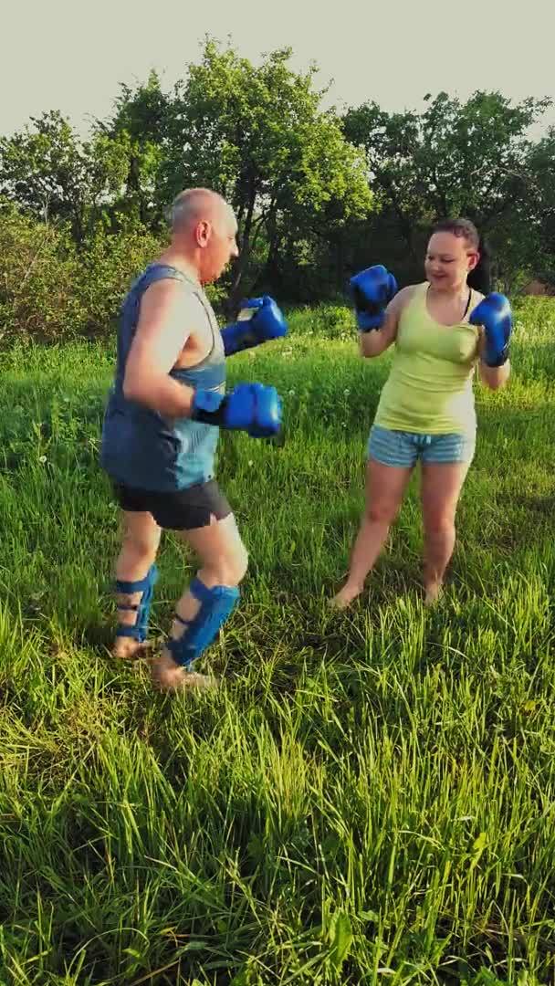 Muž a žena v parku se angažují v thajském boxu s rukavicemi vertikálně — Stock video